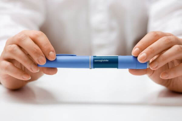 Hands holding Semaglutide injection pen.